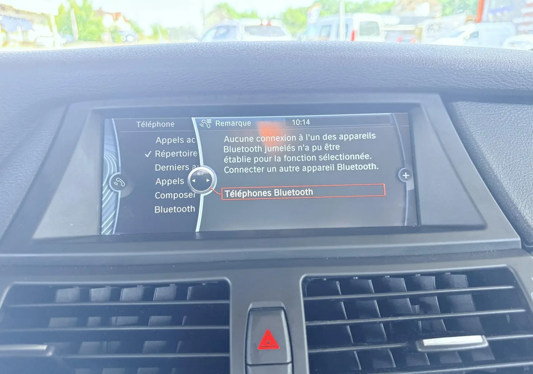 Vue intérieure centrée sur l'écran multimédia du tableau de bord du BMW X6 noir, affichant le menu Bluetooth.