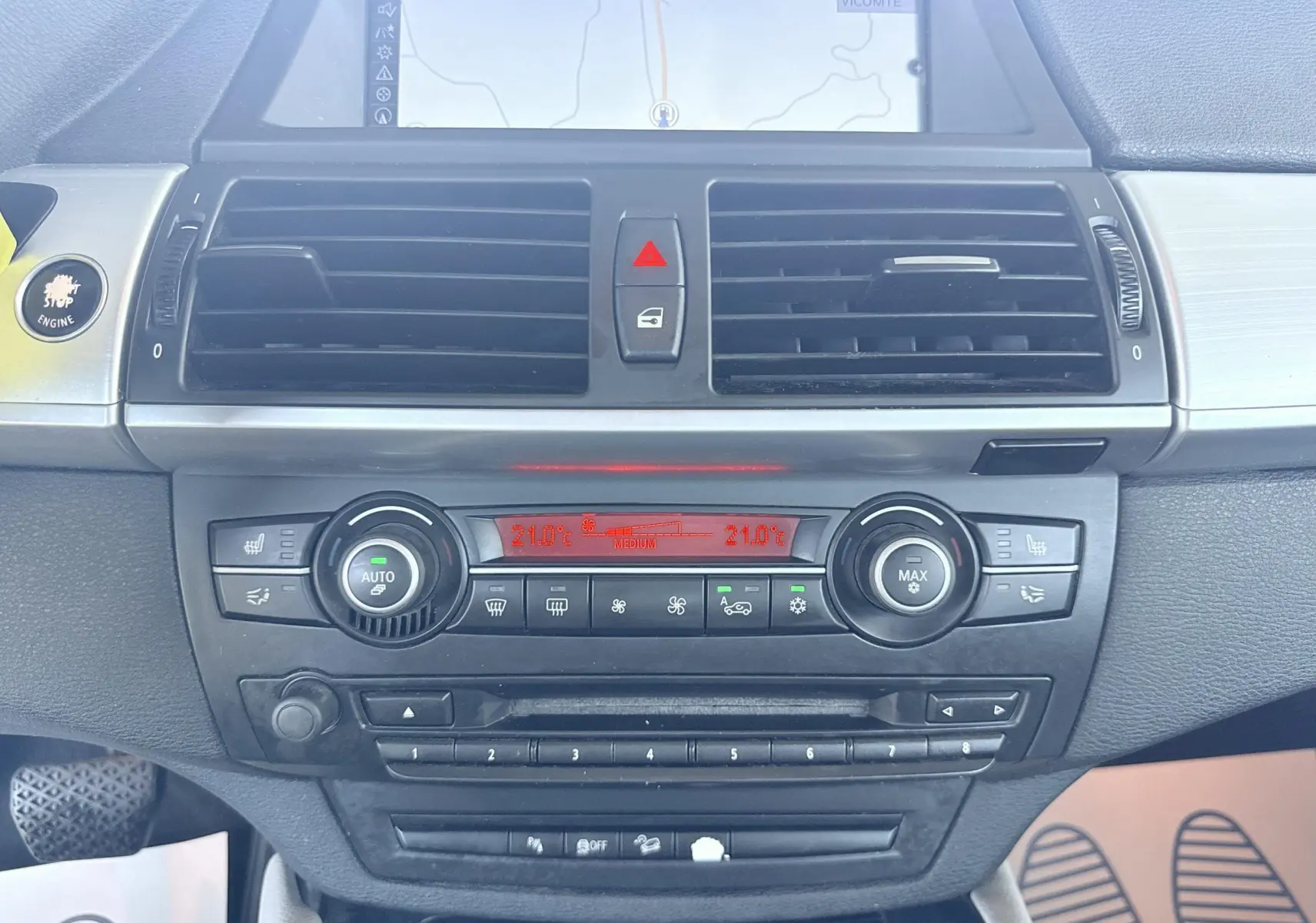 Vue rapprochée du tableau de bord noir de la BMW X6 2011, avec commandes de climatisation et écran de navigation allumé.