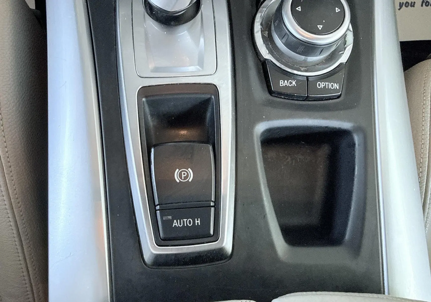 Vue rapprochée de la console centrale grise et noire du BMW X6 noire, avec commandes électroniques et molette de navigation.