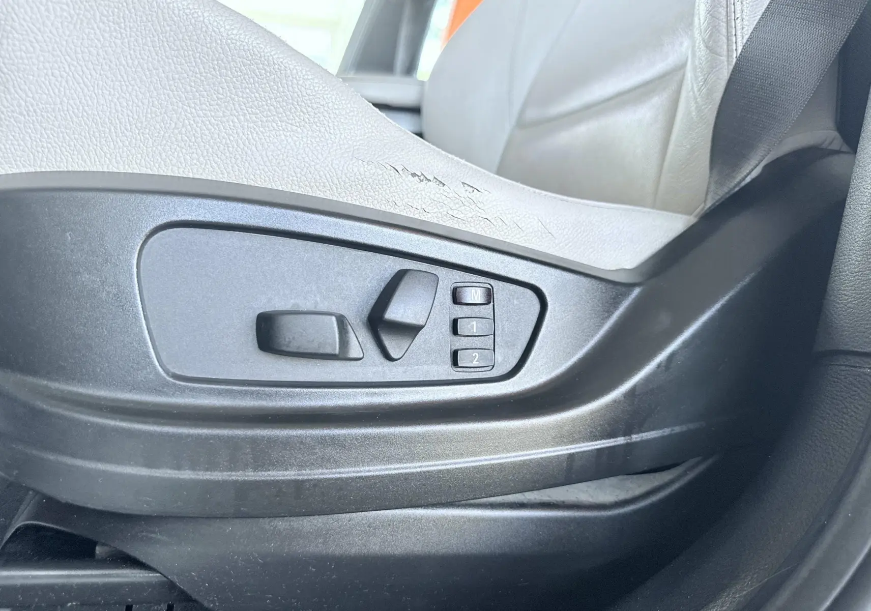Détail des commandes de réglage électrique du siège avant en cuir noir d’une BMW X6 noire.