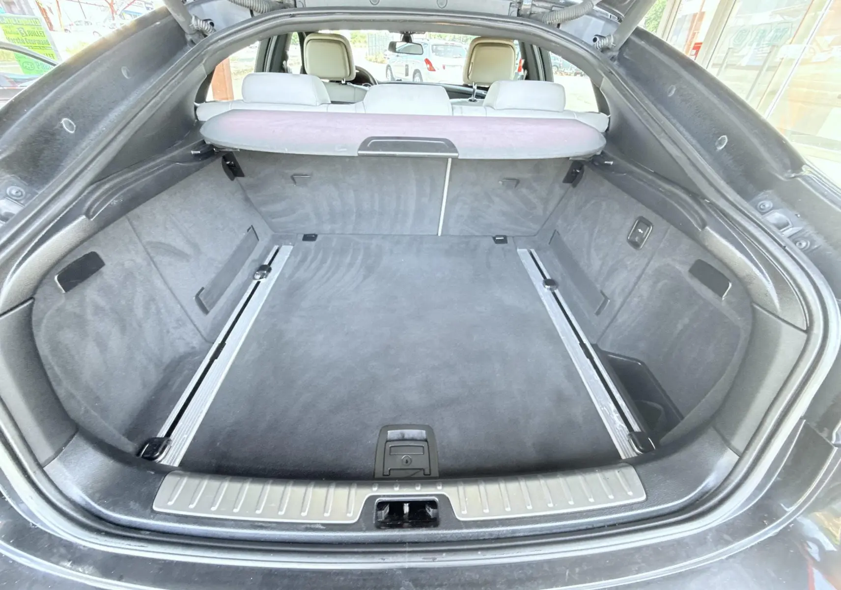 Vue depuis l'arrière du coffre spacieux et propre du BMW X6 noir, avec banquette arrière visible et cache-bagages déployé.