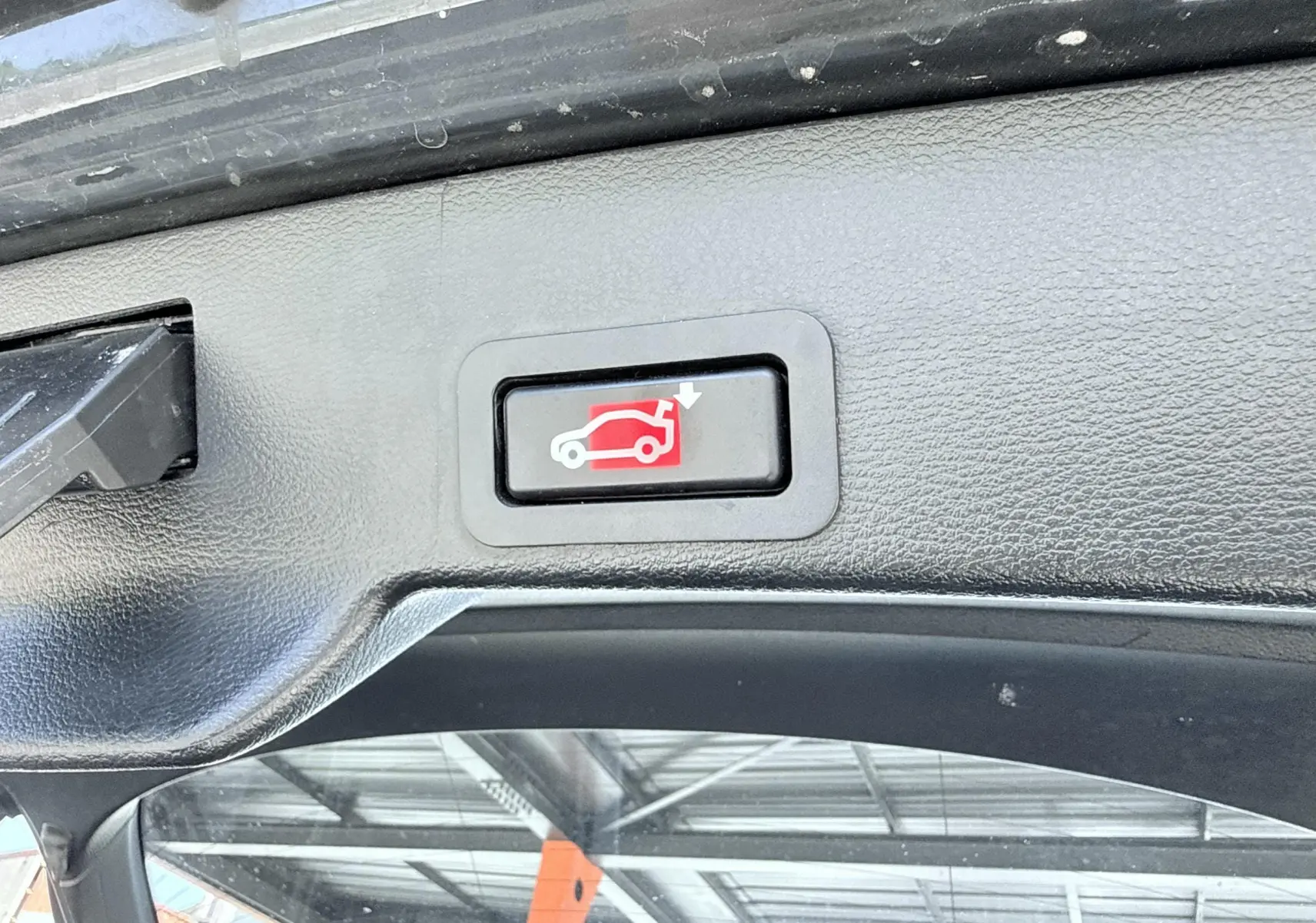 Bouton de fermeture électrique du coffre sur le bord intérieur du hayon d’un BMW X6 noir, vue rapprochée.