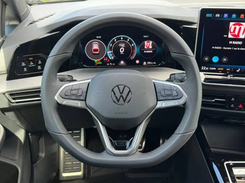 Vue intérieure centrée sur le volant cuir multifonction et le tableau de bord numérique de la Volkswagen Golf noire.