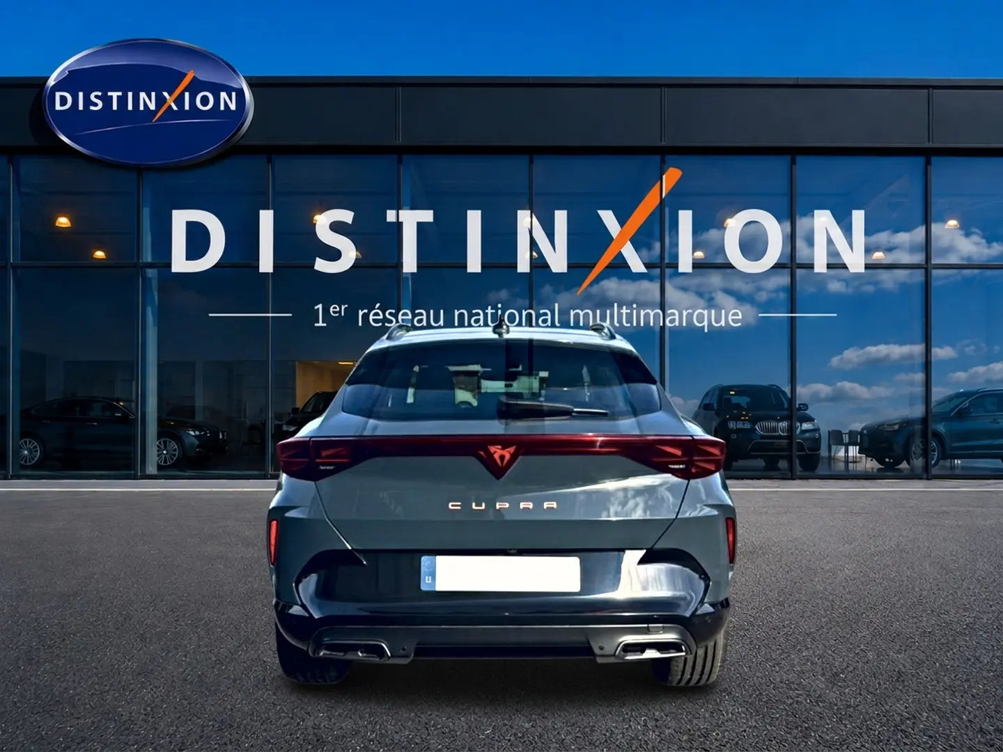 Vue arrière d'une CUPRA Formentor bleu fjord 2026 avec feux LED et double sortie d'échappement, devant un showroom Distinxion.
