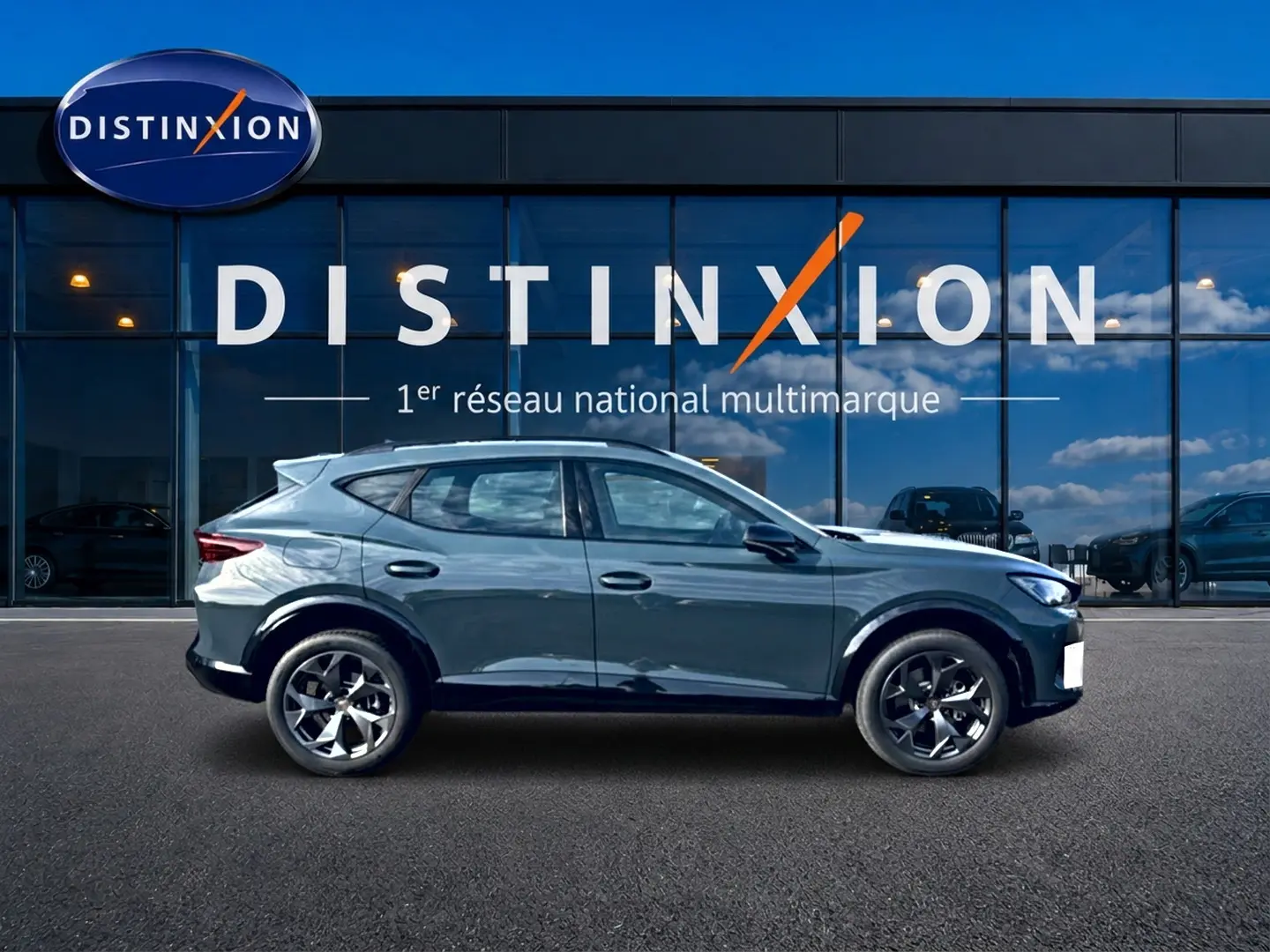 Vue de profil côté gauche du CUPRA Formentor 1.5 etsi hybrid 150 DSG7 en bleu fjord devant une vitrine Distinxion.