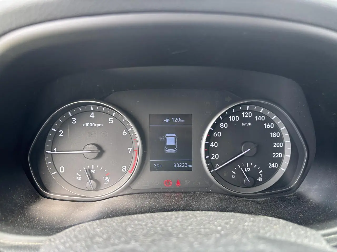 Tableau de bord de Hyundai i30 blanc 2018, affichant compte-tours, vitesse, température et écran central digital.