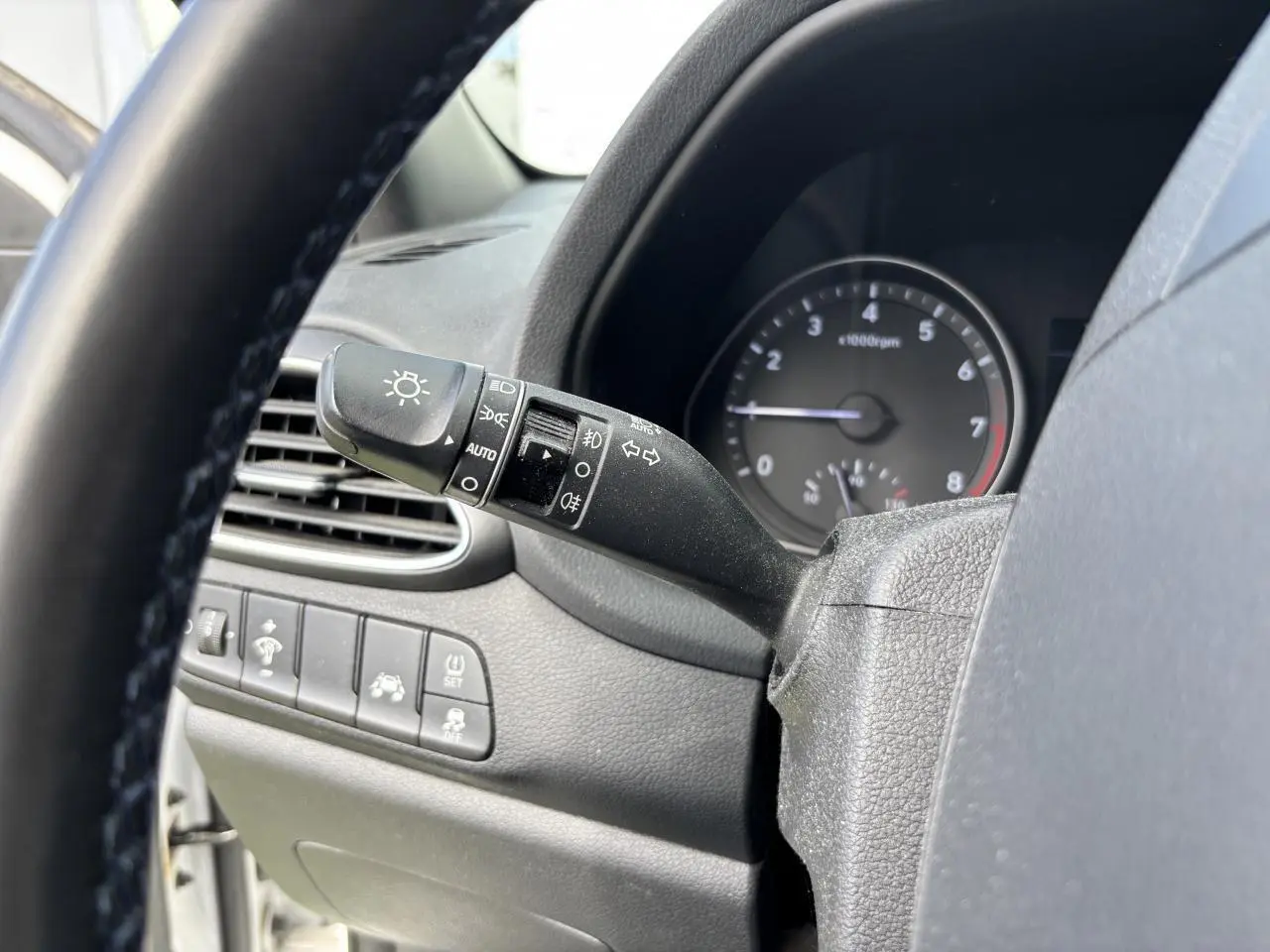 Gros plan sur la manette des feux et clignotants à gauche du volant d'une Hyundai i30 blanche de 2018.