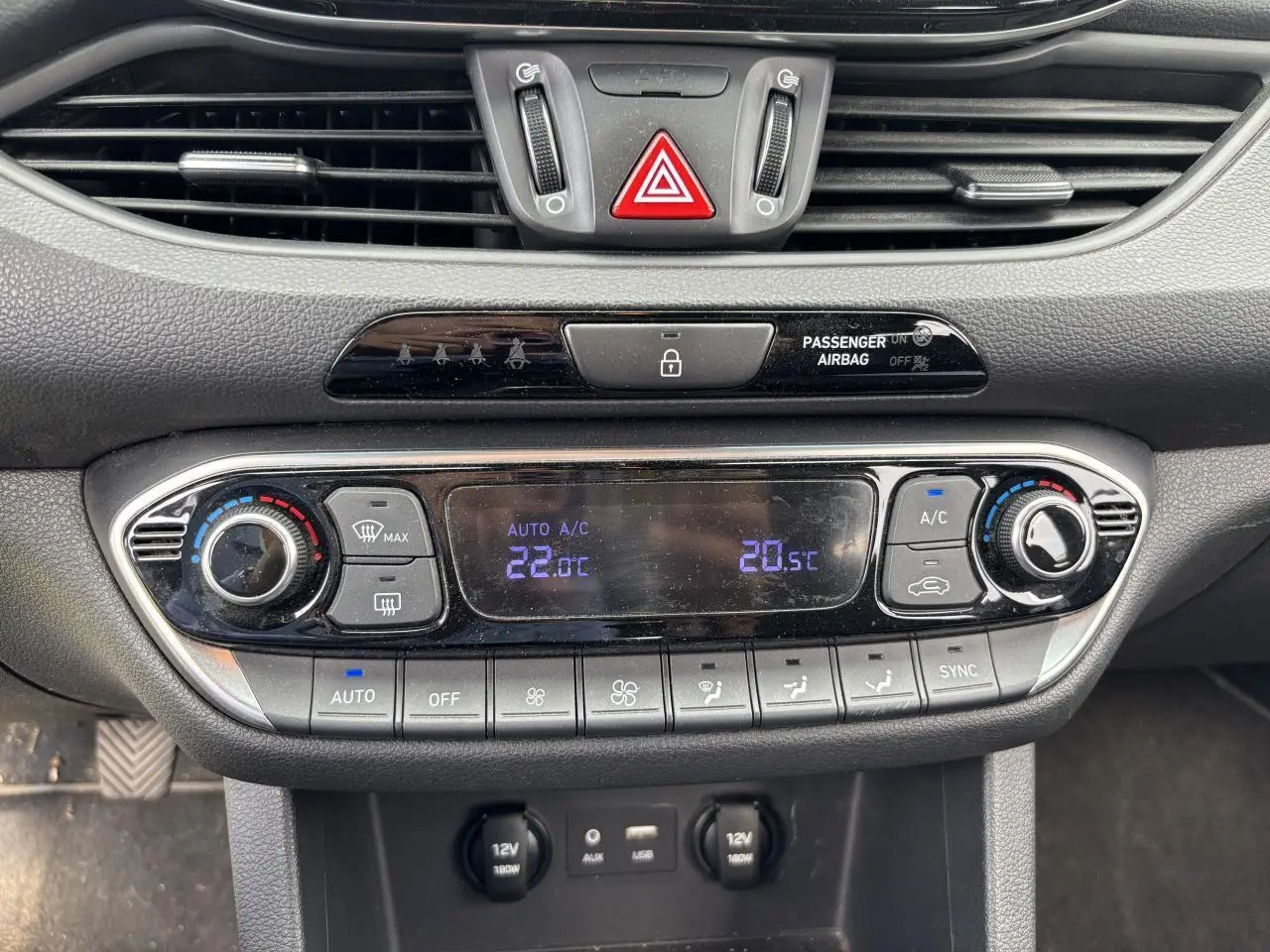 Gros plan sur la console centrale de la Hyundai i30 blanche, affichant la climatisation automatique bi-zone et les commandes tactiles.