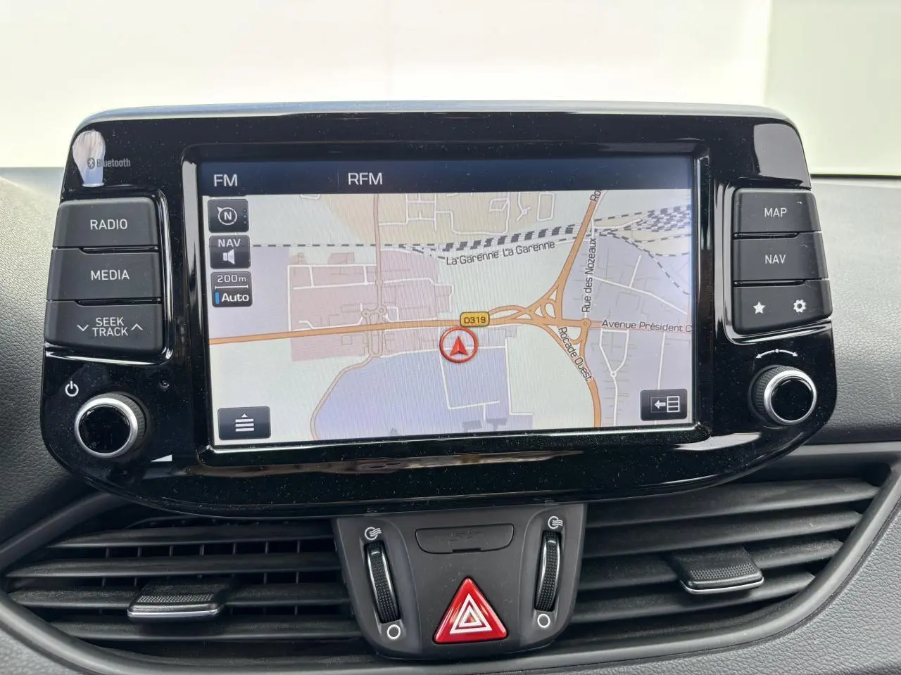 Écran tactile central du système de navigation de la Hyundai i30 III SW Edition Navi, avec commandes autour et tableau de bord noir.