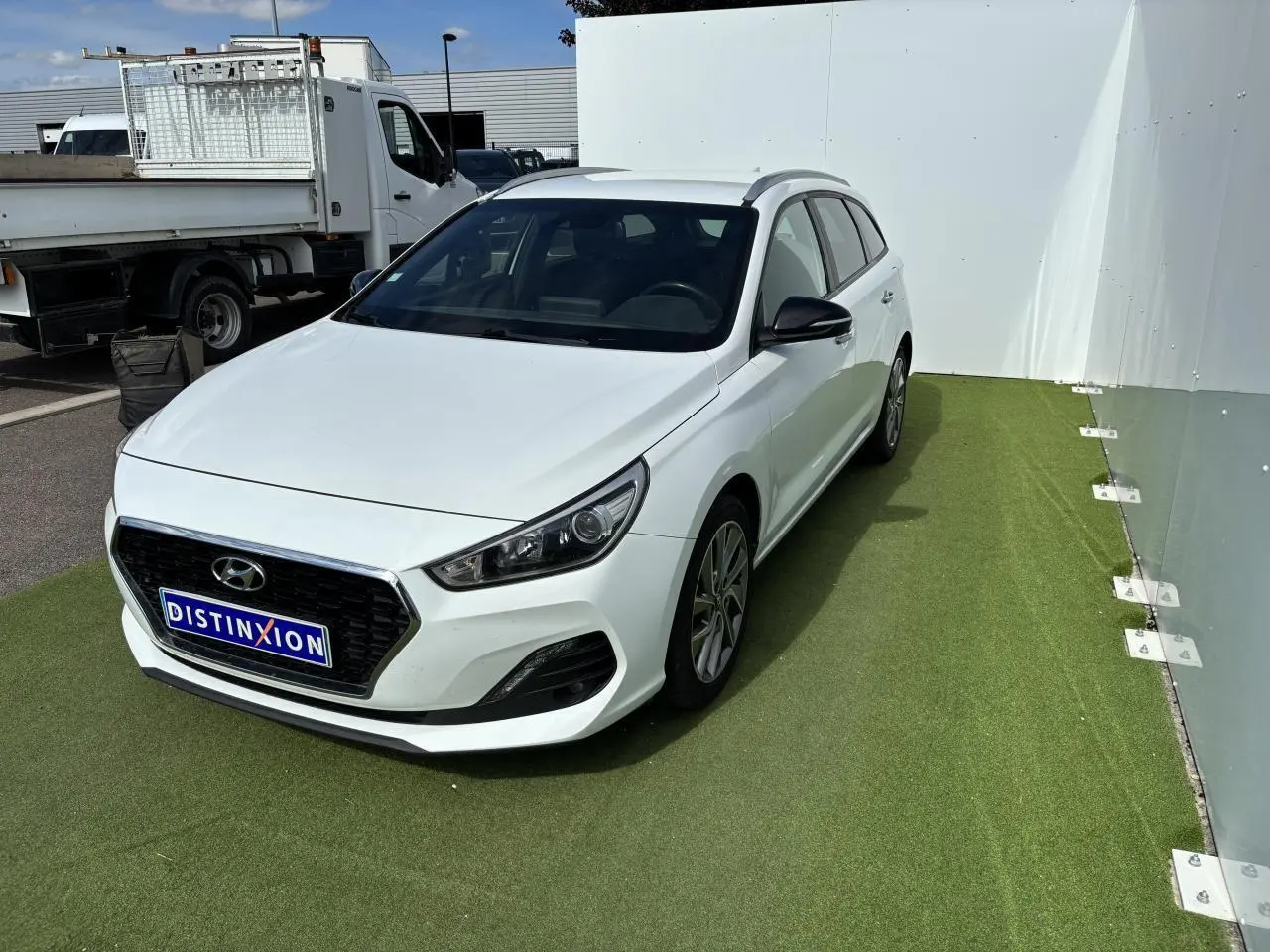 Hyundai i30 SW blanche vue en 3/4 avant droit, avec calandre noire et jantes alliage 17 pouces.