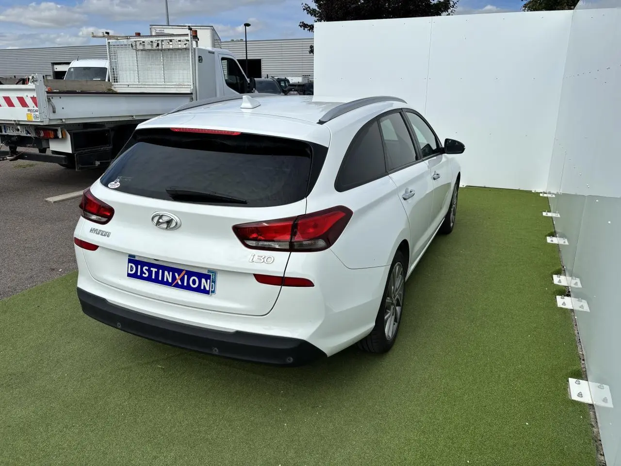 Vue 3/4 arrière droite d'une Hyundai i30 SW blanche avec vitres arrière surteintées et jantes alliage 17 pouces.