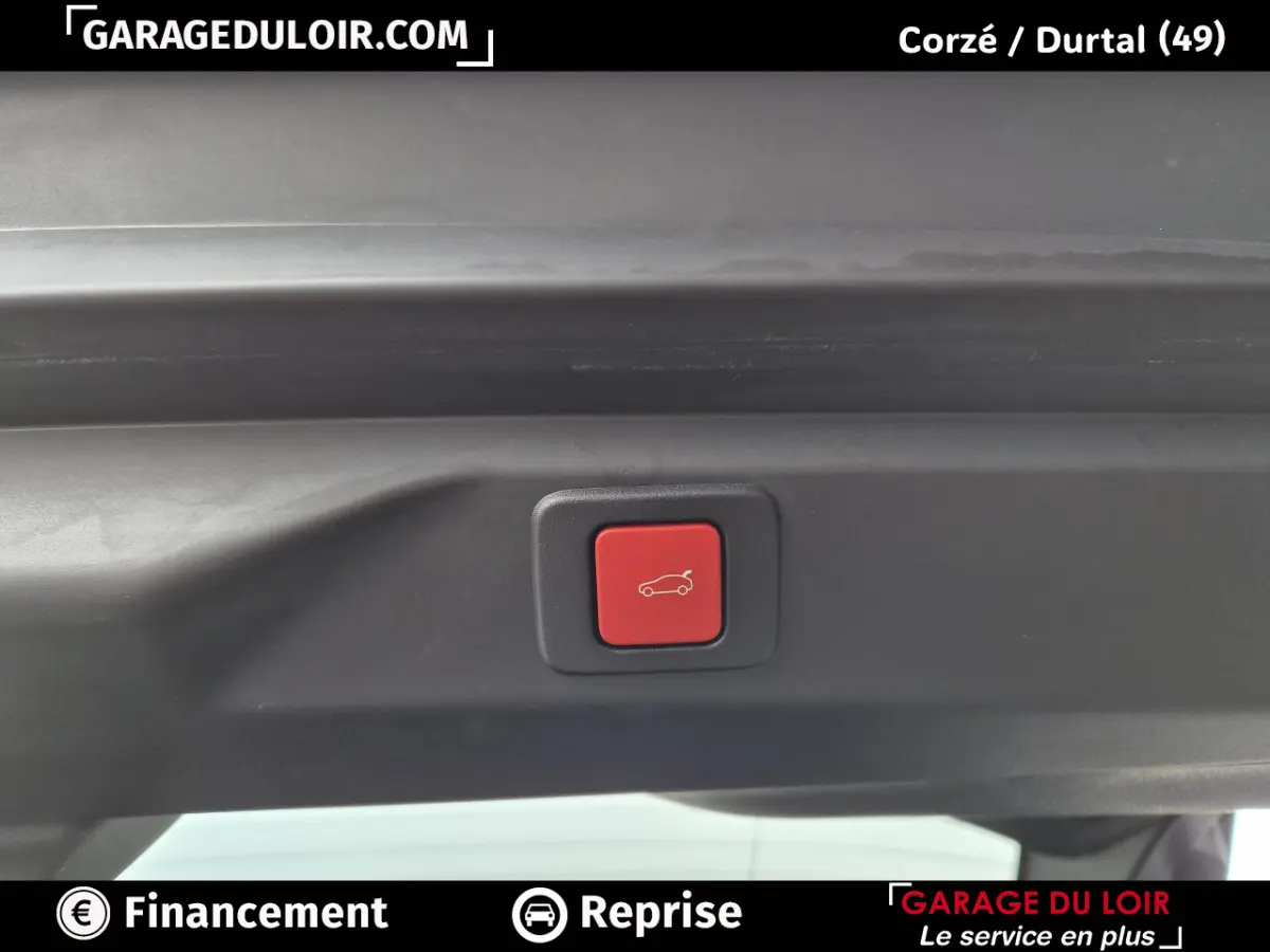 Bouton rouge d'ouverture électrique du coffre sur la partie intérieure du hayon d'un Peugeot 3008 blanc.