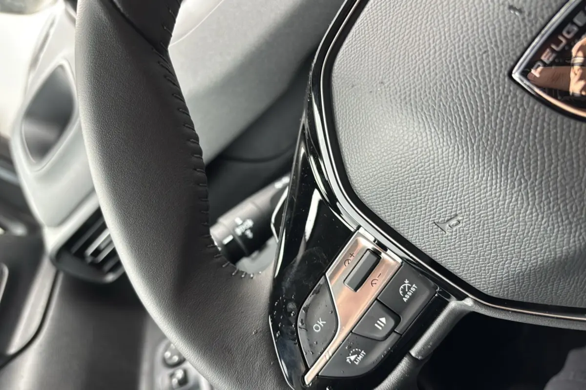 Gros plan sur le volant cuir noir multifonctions du Peugeot Rifter 2026, mettant en valeur les commandes intégrées.