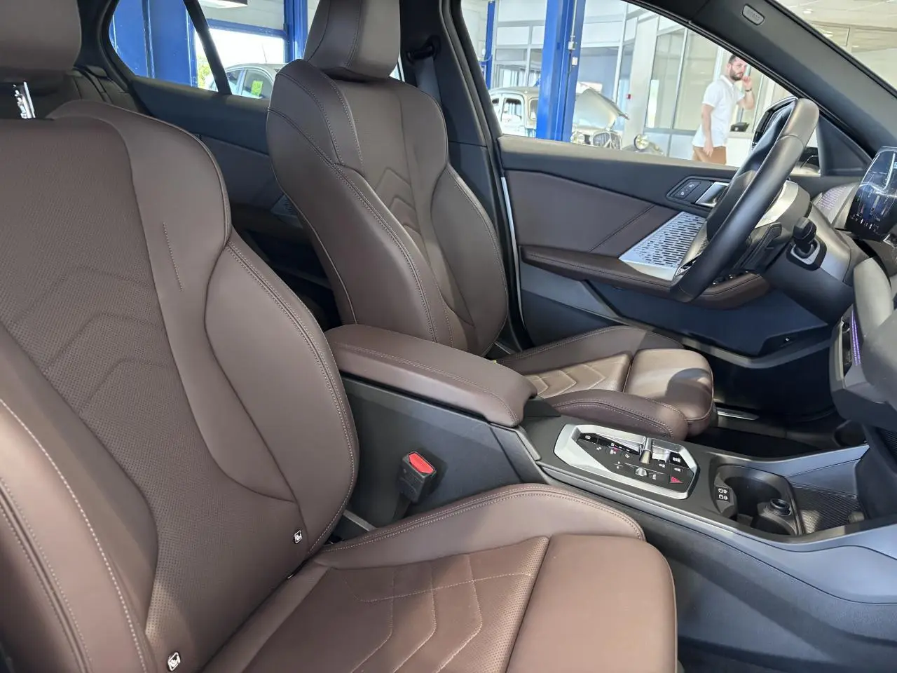 Vue intérieure côté conducteur de la BMW Série 1 120d M Sport 2025 avec sièges en cuir marron et console centrale moderne.
