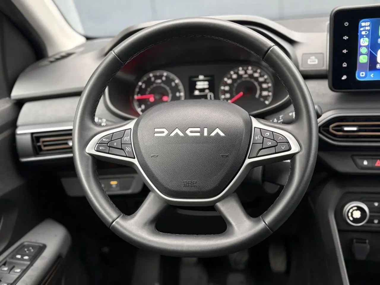 Vue intérieure centrée sur le volant noir de la Dacia Sandero Stepway 2025 avec tableau de bord et écran tactile.