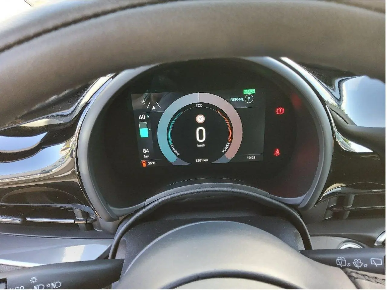 Vue rapprochée du tableau de bord numérique de la Fiat 500 électrique 2024, affichant l'autonomie et la vitesse à 0 km/h.