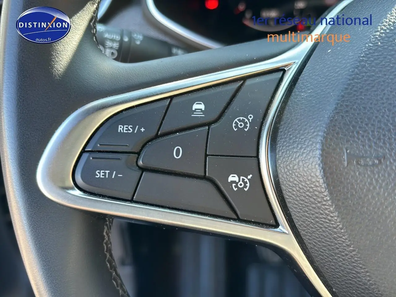 Gros plan sur les commandes de régulateur de vitesse au volant textile enduit gris de la Renault Clio V 2024.