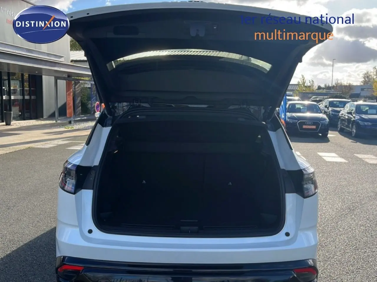Vue arrière d'un Renault Austral Iconic Esprit Alpine blanc et noir avec coffre ouvert sur un parking.