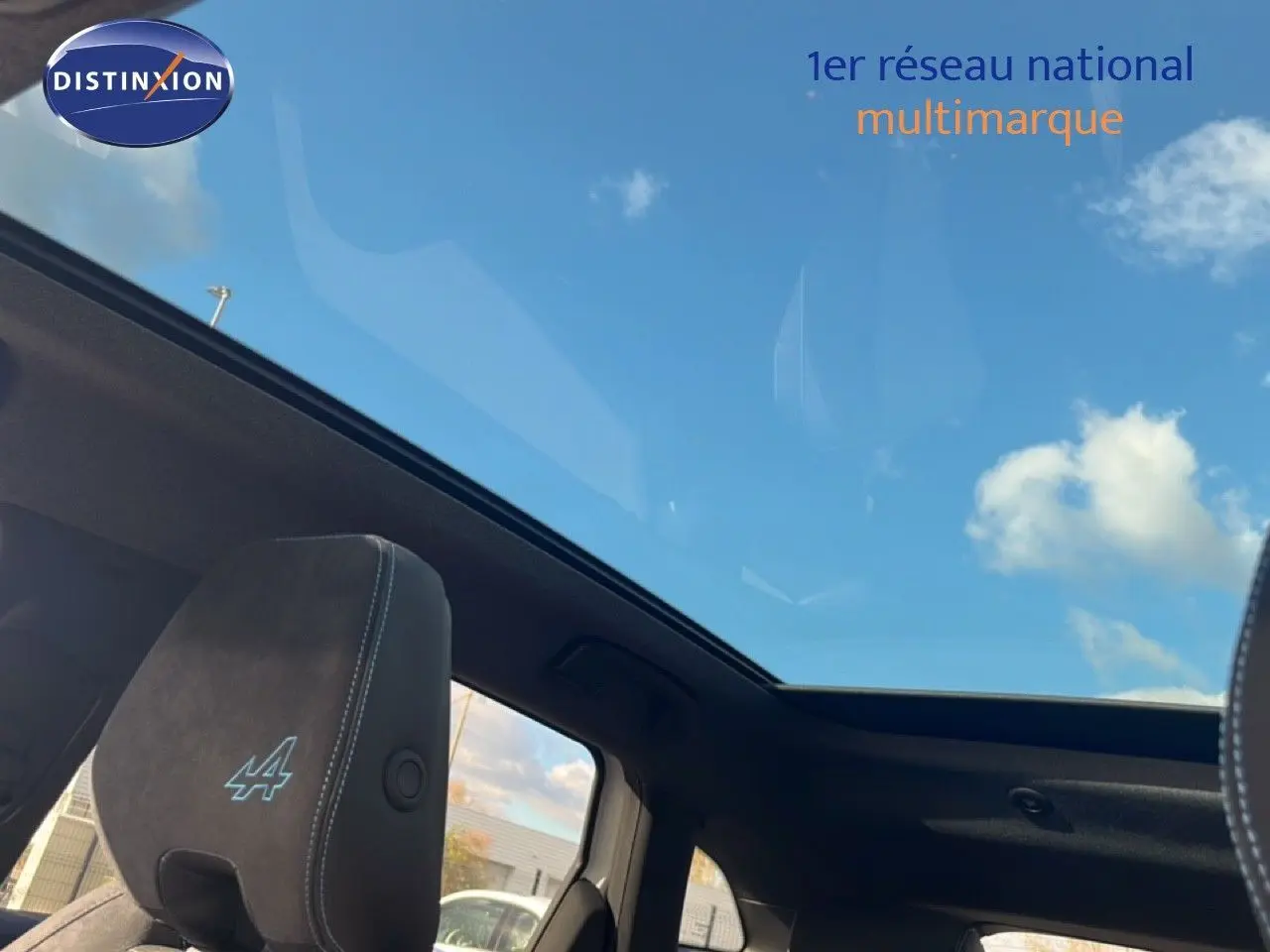 Toit panoramique ouvert vu de l'intérieur sur les sièges noirs avec logo Alpine du Renault Austral Iconic Esprit Alpine.