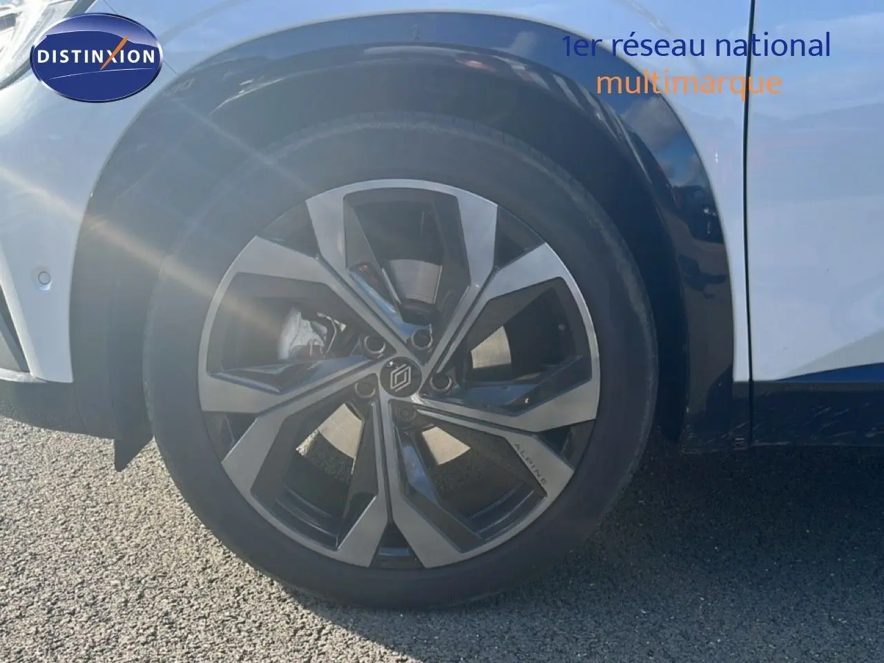 Gros plan sur la roue avant gauche du Renault Austral Iconic Esprit Alpine blanc et noir, jante alu distinctive.