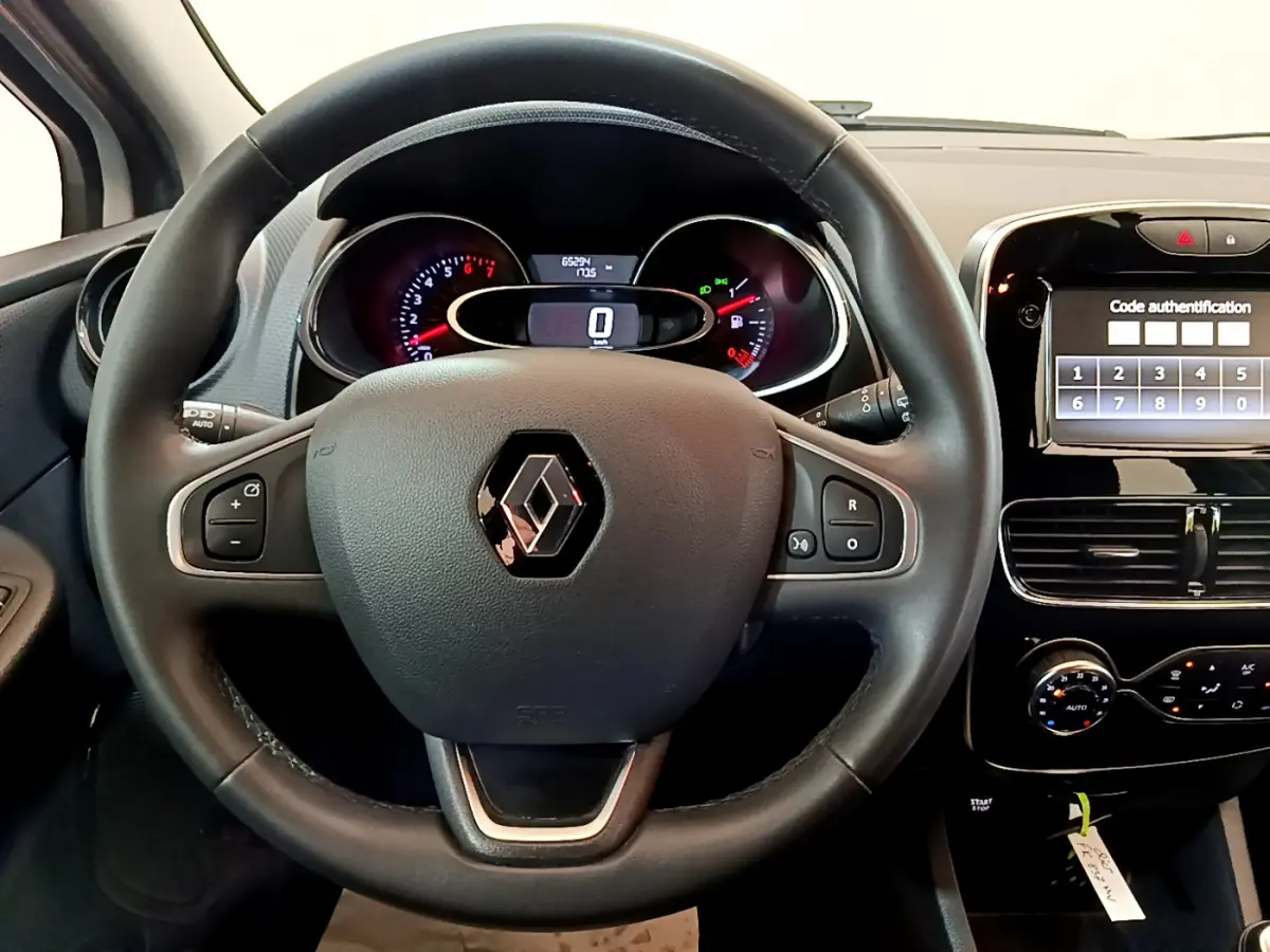 Vue intérieure centrée sur le volant cuir noir de la Renault Clio Business avec tableau de bord et écran tactile allumé.