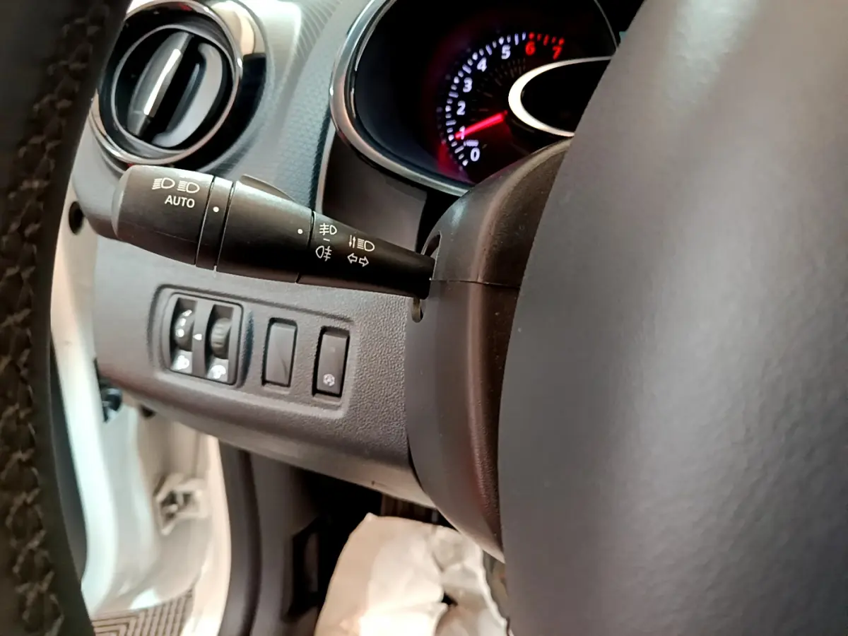 Gros plan sur le volant et la commande des feux de la Renault Clio Business TCe 90 blanche de 2019, intérieur noir.