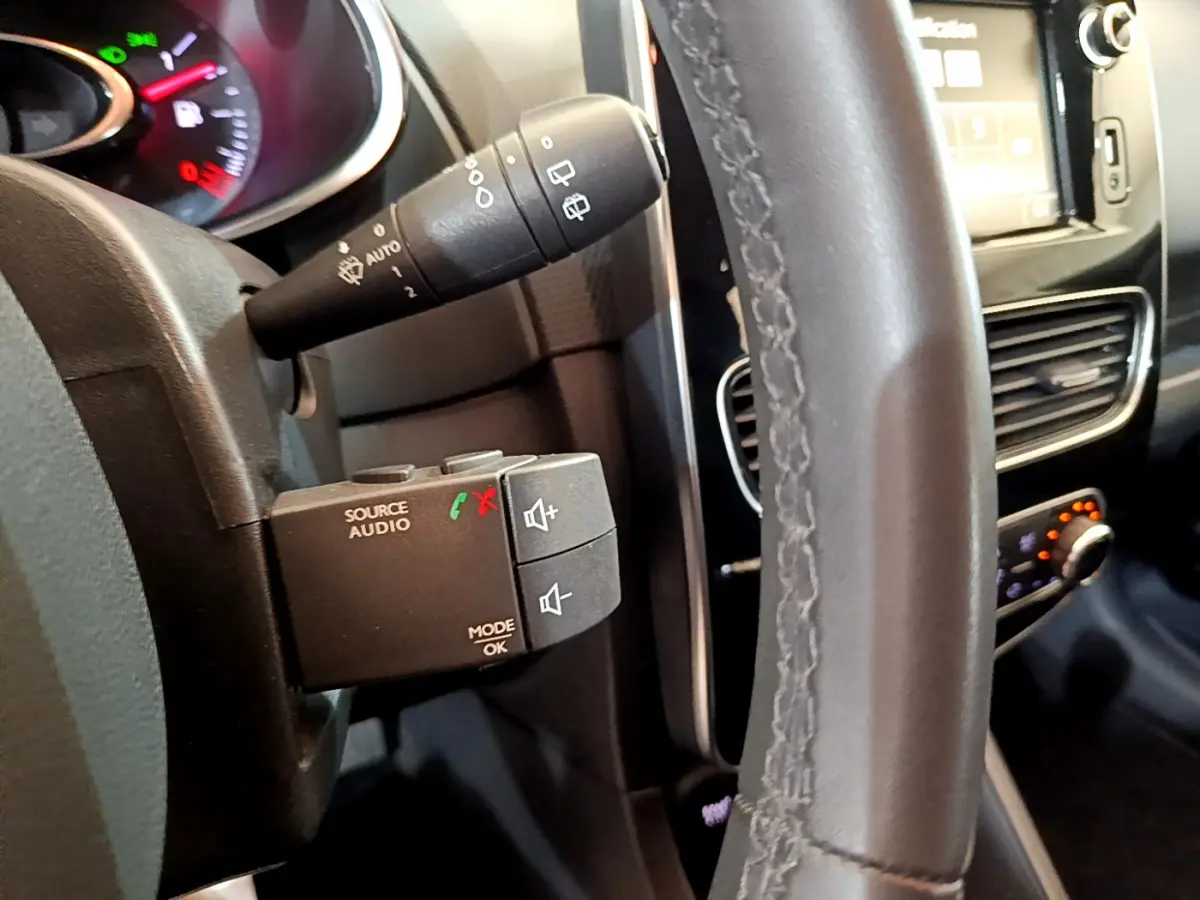 Gros plan sur le volant cuir et commandes audio au volant de la Renault Clio Business TCe 90 blanche de 2019.