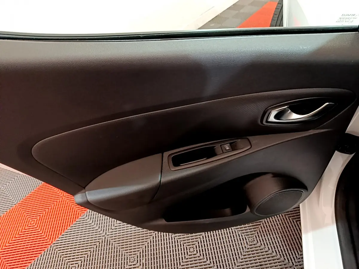 Vue rapprochée de la porte côté conducteur d'une Renault Clio Business blanche, avec poignée et commande de vitre noire.