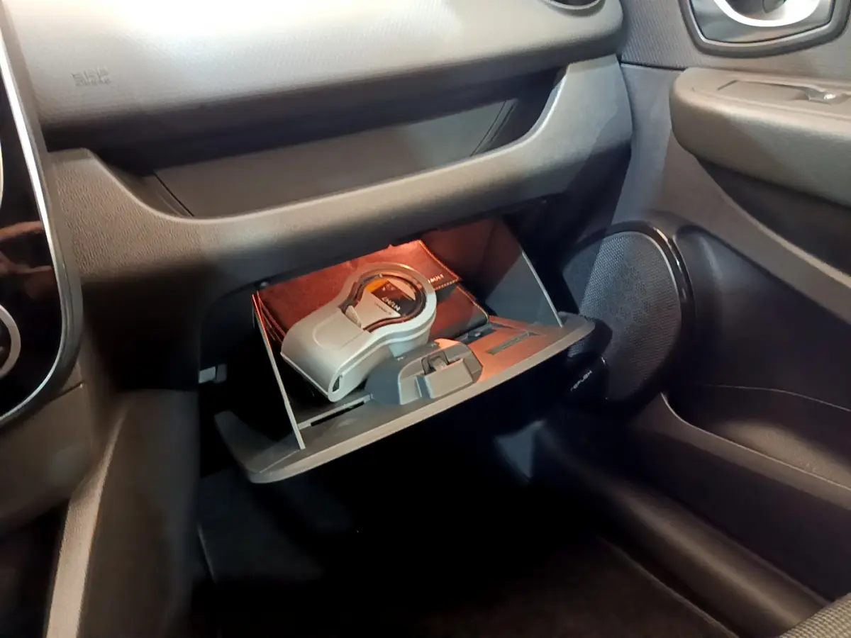 Vue rapprochée de la boîte à gants ouverte côté passager d'une Renault Clio Business blanche avec objets à l'intérieur.
