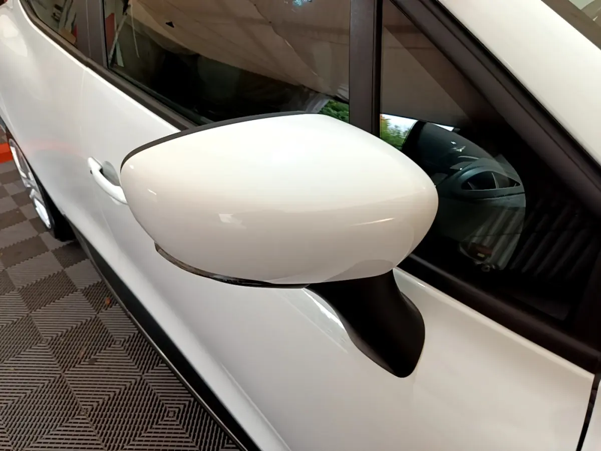 Gros plan sur le rétroviseur côté gauche blanc d'une Renault Clio Business TCe 90 blanche, avec porte et vitre visibles.