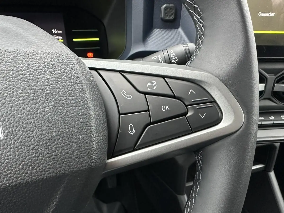 Gros plan sur les commandes au volant côté droit du Dacia Duster 2025 noir, avec tableau de bord partiellement visible.