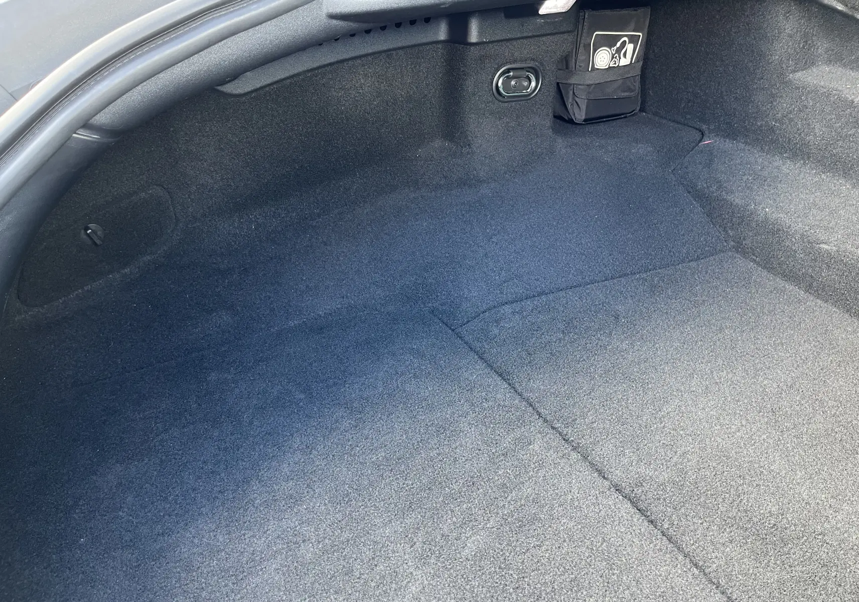 Vue rapprochée de l'espace de coffre tapissé de moquette noire dans une Jaguar F-TYPE II COUPE 2.0T 2018 gris Corris.