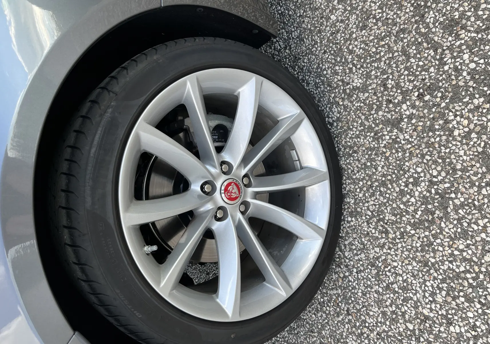 Gros plan sur la jante avant droite 19 pouces argentée de la Jaguar F-TYPE II Coupe Corris Grey avec logo rouge au centre.