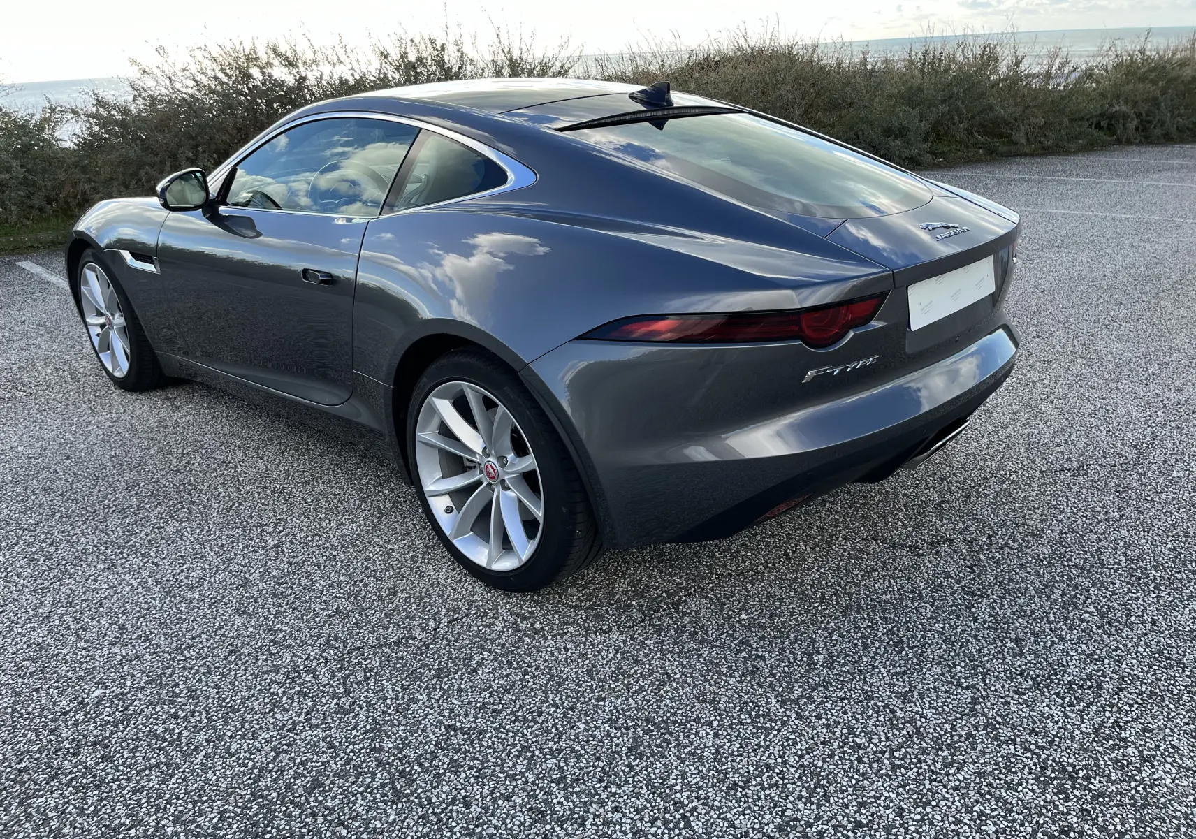 Jaguar F-TYPE Coupé 2018 gris Corris, vue 3/4 arrière droit, jantes 19 pouces et feux arrière étirés.