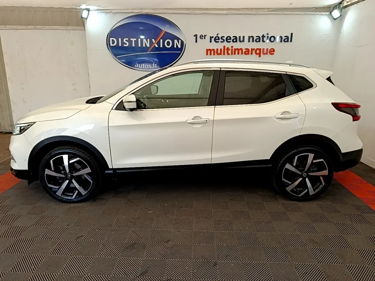 Vue de profil côté gauche d'un Nissan Qashqai blanc 2019 avec jantes alliage et toit spoiler dans un showroom.
