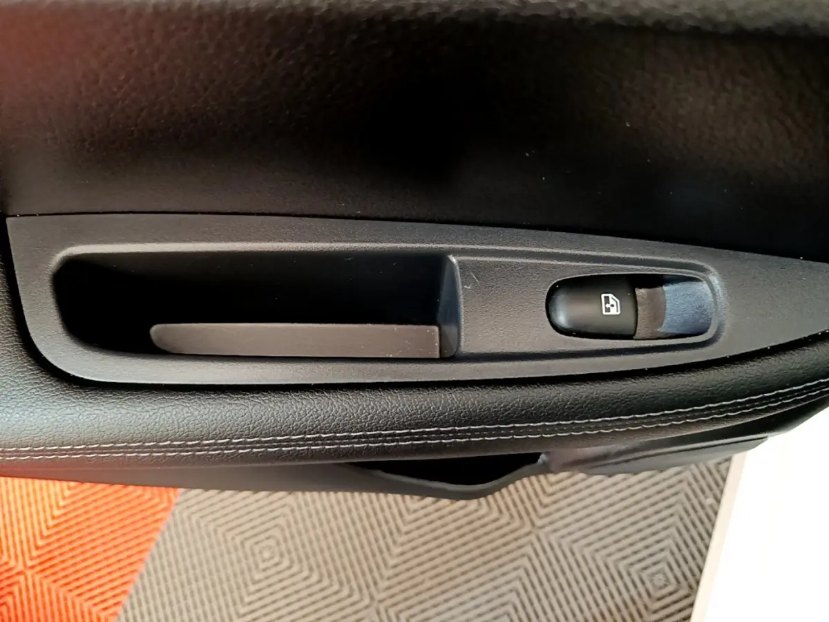 Détail de la commande de lève-vitre sur la porte intérieure noire d'un Nissan Qashqai blanc 2019.