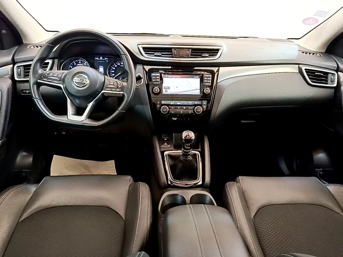 Vue intérieure frontale du tableau de bord noir du Nissan Qashqai 1.3 DIG-T 140 Tekna avec volant cuir et écran tactile central.
