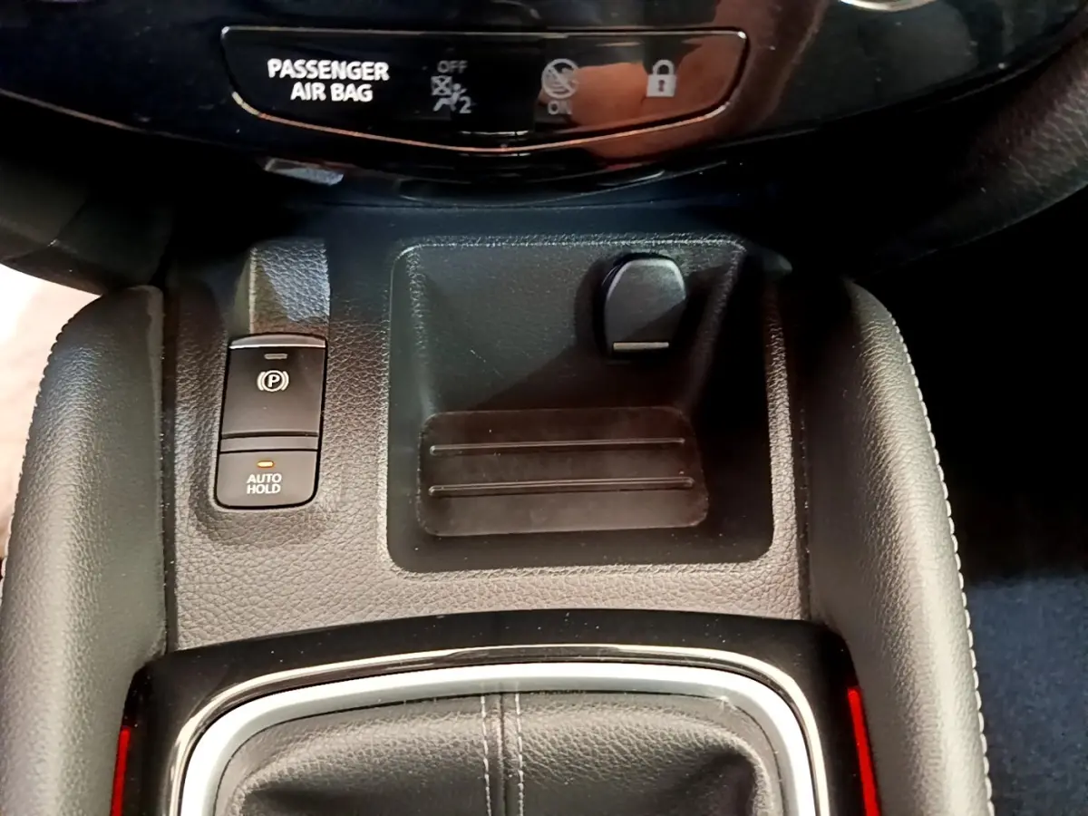 Gros plan sur la console centrale du Nissan Qashqai blanc 2019, avec frein à main électrique et bouton auto hold.
