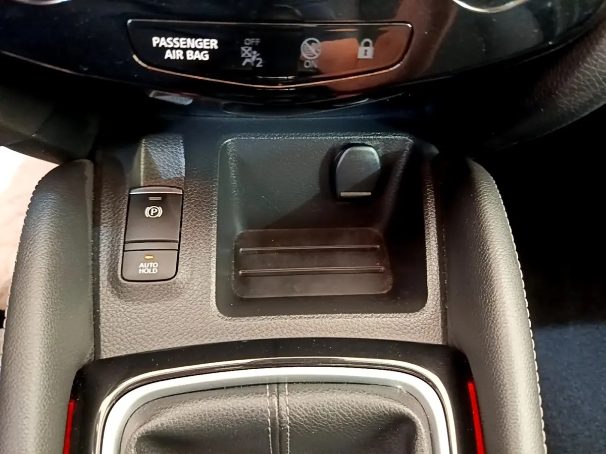 Gros plan sur la console centrale du Nissan Qashqai blanc, avec frein à main électrique et bouton Auto Hold.