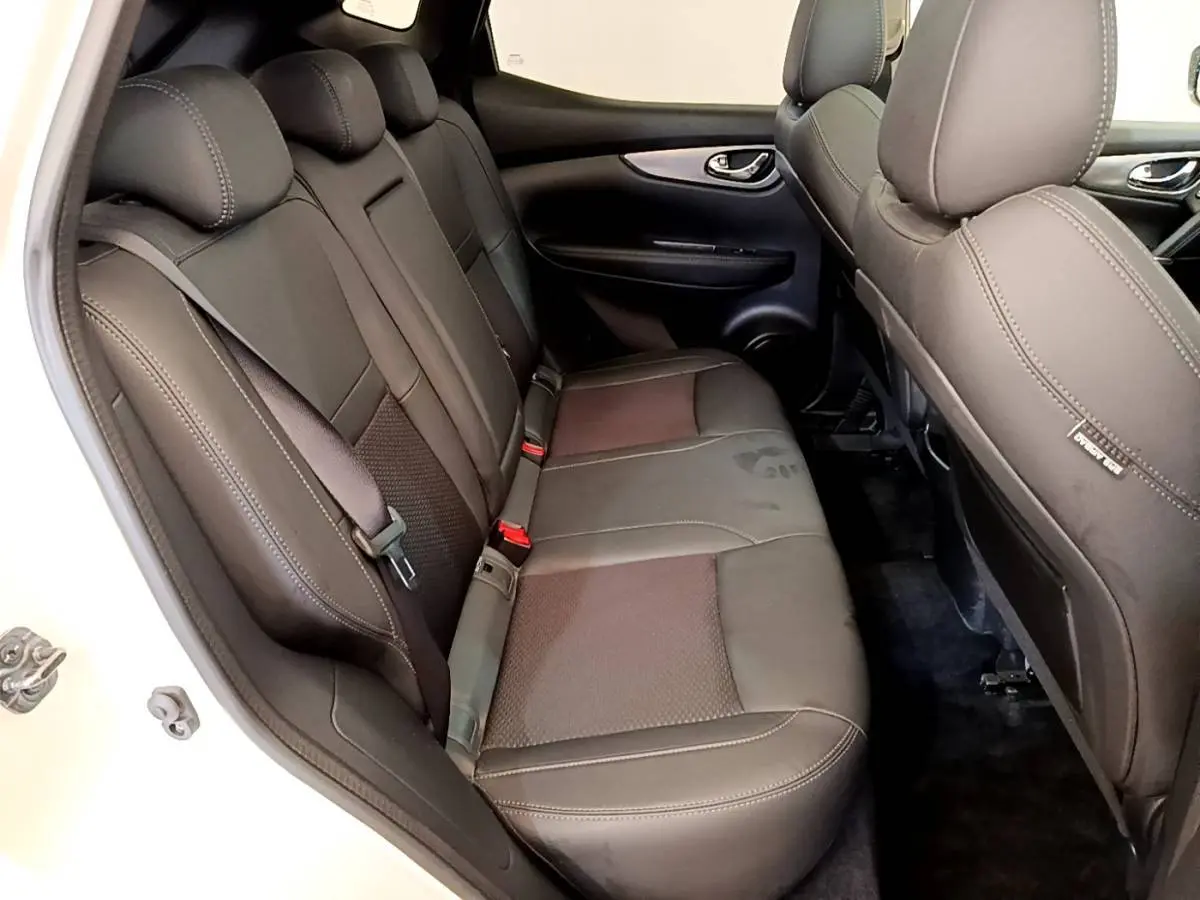 Vue côté gauche sur la banquette arrière noire du Nissan Qashqai blanc, avec ceinture de sécurité et appuie-têtes visibles.