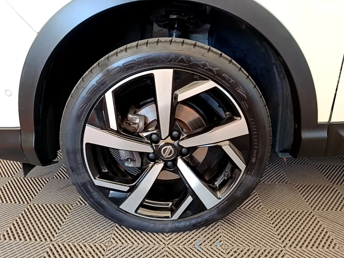 Gros plan sur la roue avant droite du Nissan Qashqai blanc, mettant en valeur la jante alliage bicolore.