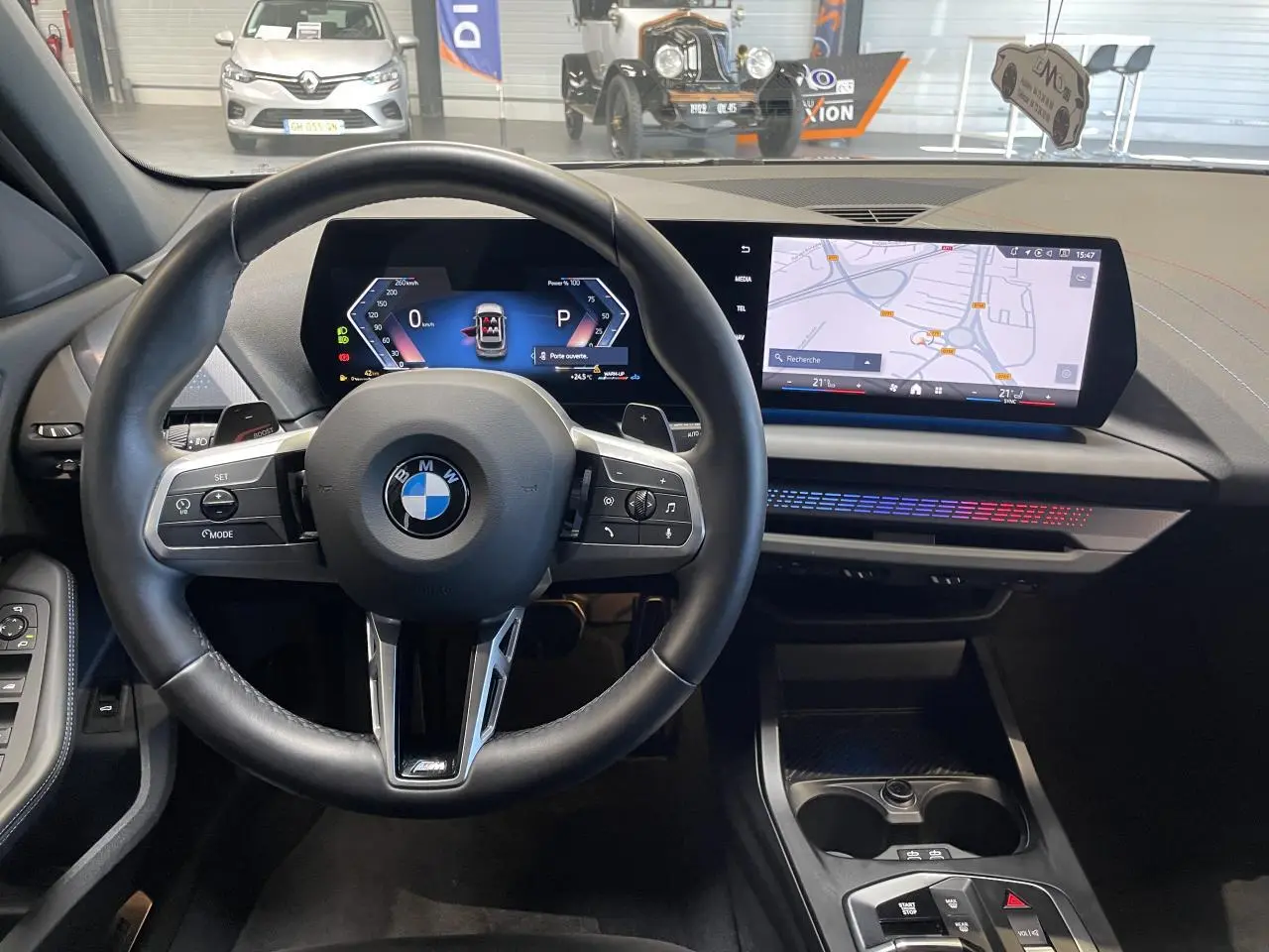 Vue intérieure centrée sur le volant BMW M Sport et le tableau de bord numérique avec écran tactile de la Série 1 gris 2025.