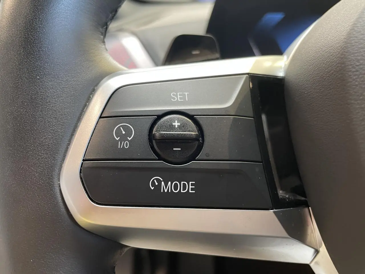 Gros plan sur les commandes de régulateur de vitesse au volant gris d'une BMW Série 1 120d M Sport 2025.