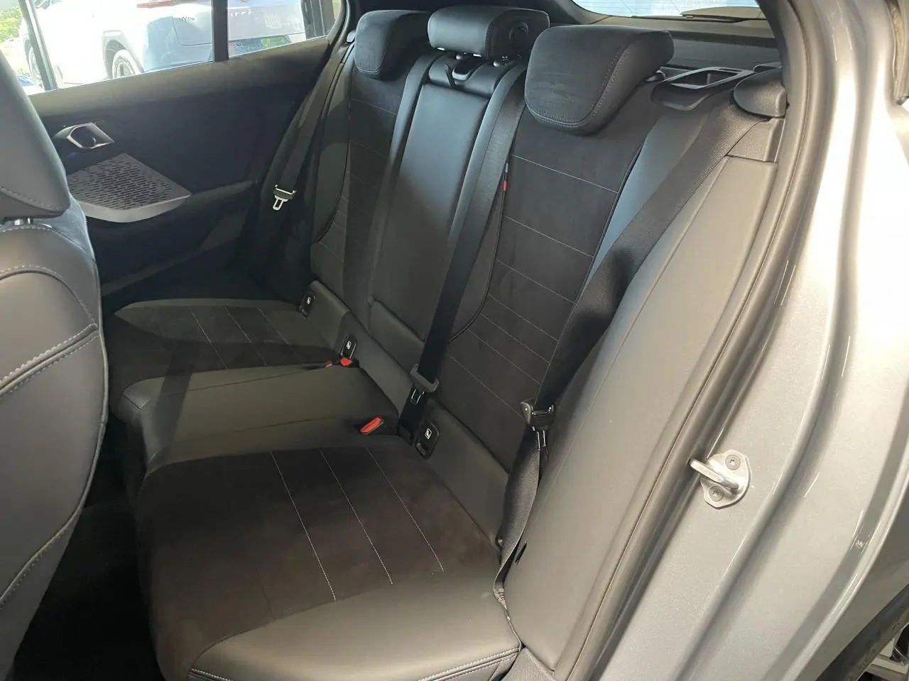 Vue intérieure côté droit des sièges arrière en cuir noir de la BMW Série 1 120d M Sport gris 2025.