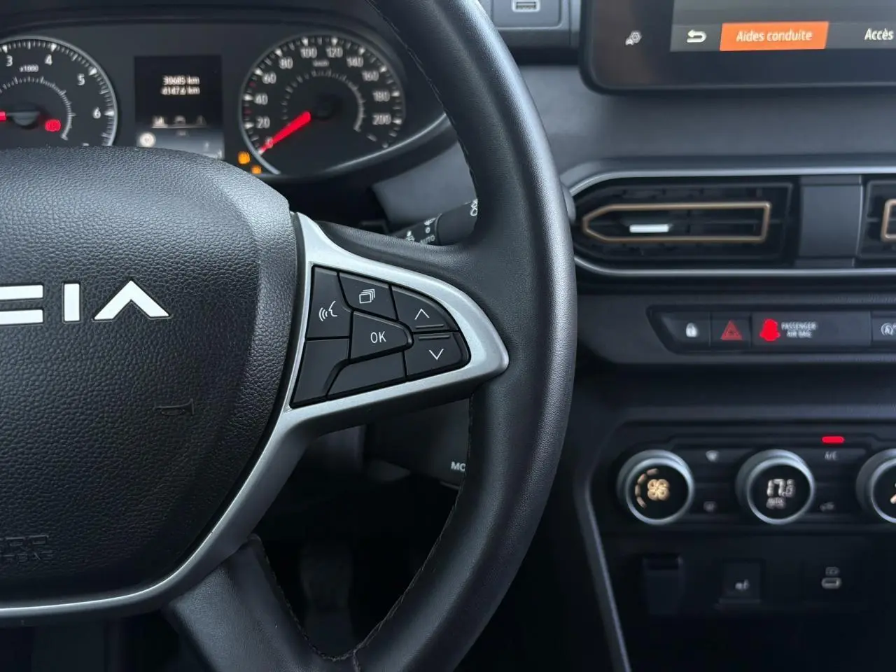 Gros plan sur le volant et tableau de bord de la Dacia Sandero Stepway 2025, avec commandes au volant et écran tactile visible.