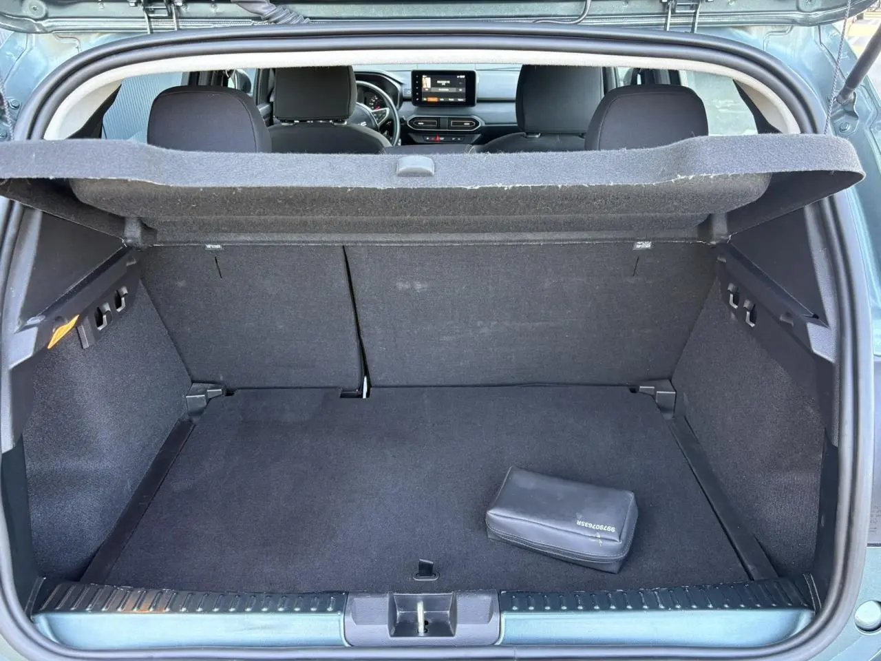 Coffre ouvert vu de l'arrière d'une Dacia Sandero Stepway Vert Cèdre, banquette arrière et tableau de bord visibles.