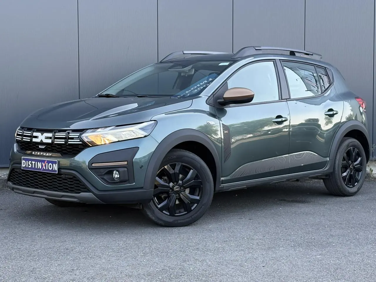 Dacia Sandero Stepway 2025 Vert Cèdre en 3/4 avant droit avec jantes noires et coques de rétroviseur cuivrées.