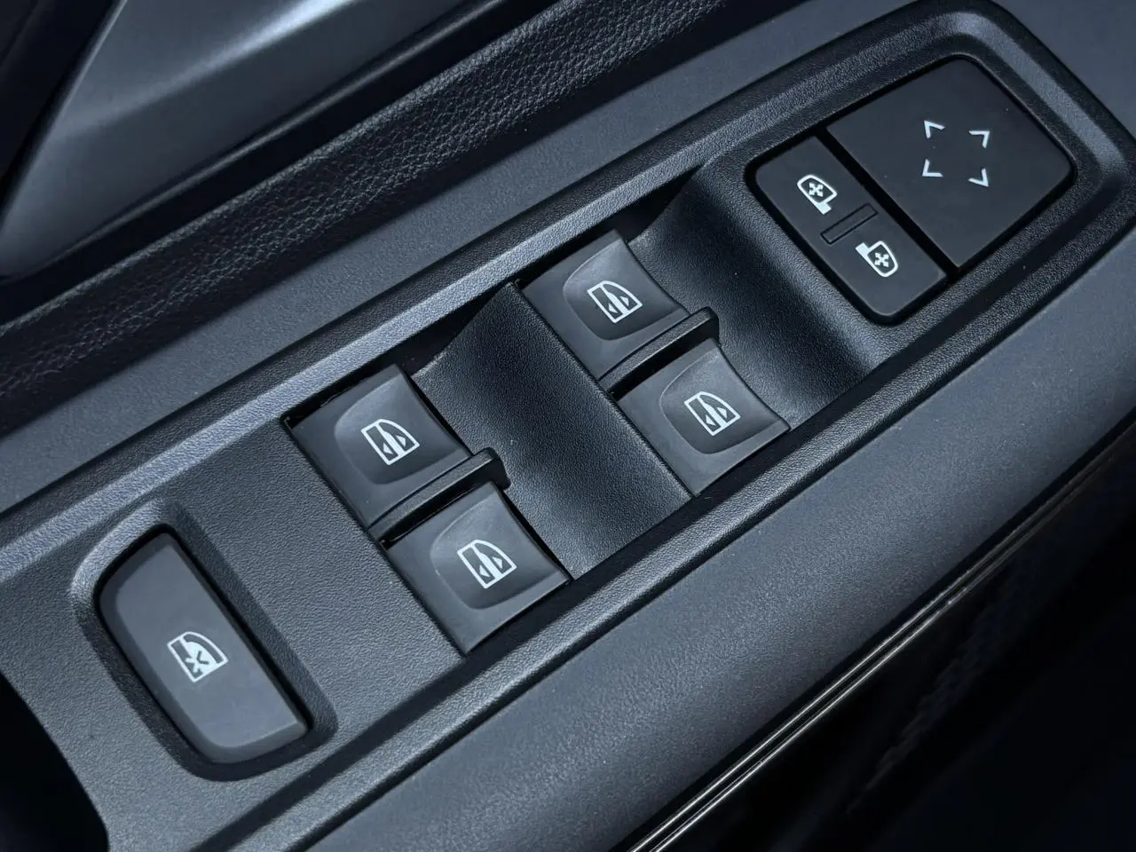 Gros plan sur les commandes de lève-vitres et réglages des rétroviseurs côté conducteur de la Dacia Sandero Stepway Vert Cèdre.