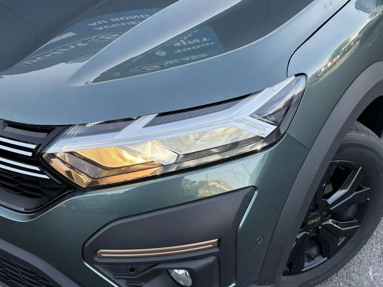Gros plan sur l'avant droit vert cèdre du Dacia Sandero Stepway 2025 avec phare LED et jante aluminium noire.