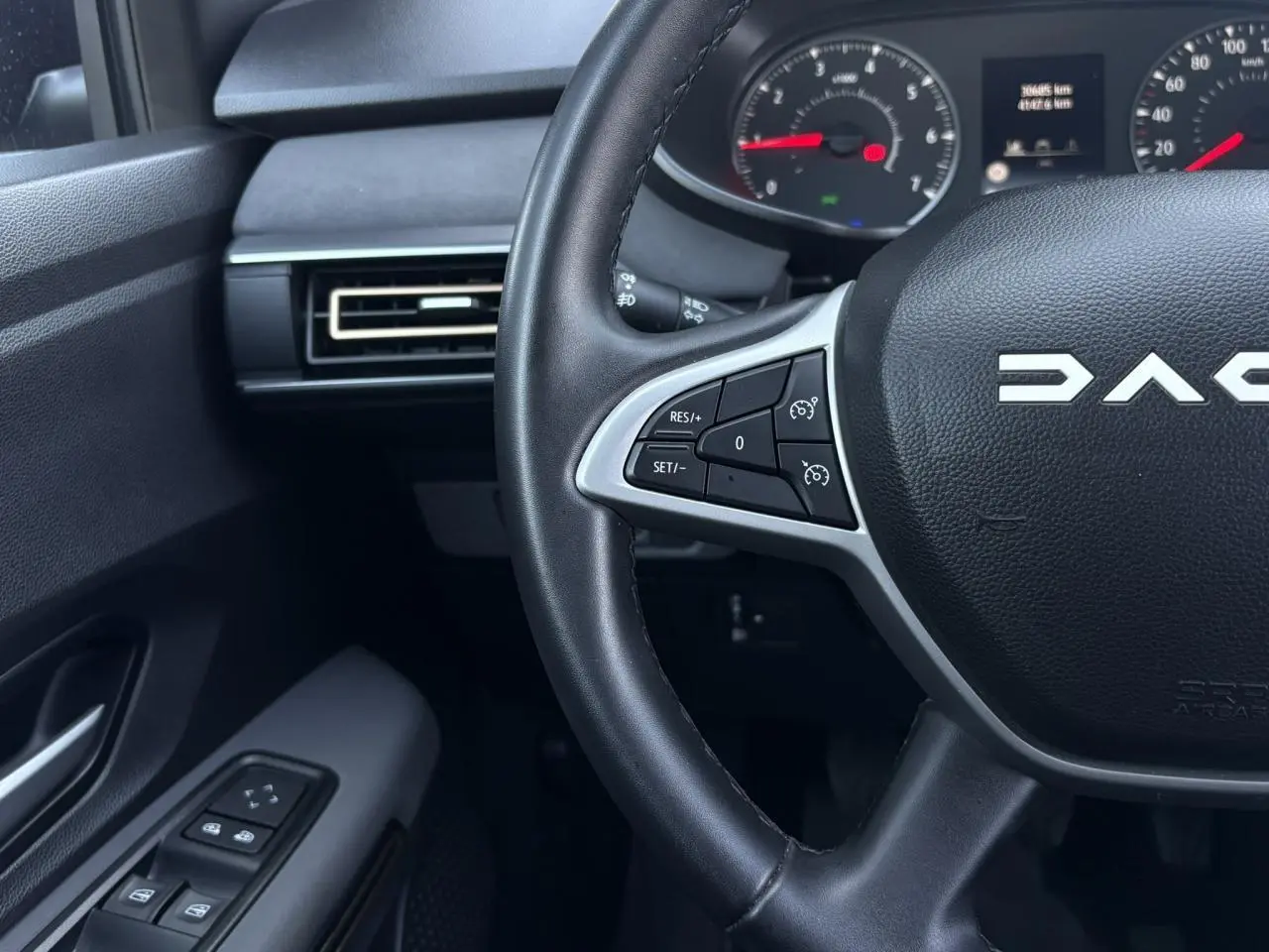Vue intérieure rapprochée du volant noir Dacia Sandero Stepway avec commandes au volant et tableau de bord partiel.